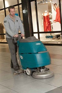 cleaning staff using Tenant T2 walk behind floor scrubber to clean department store entry way